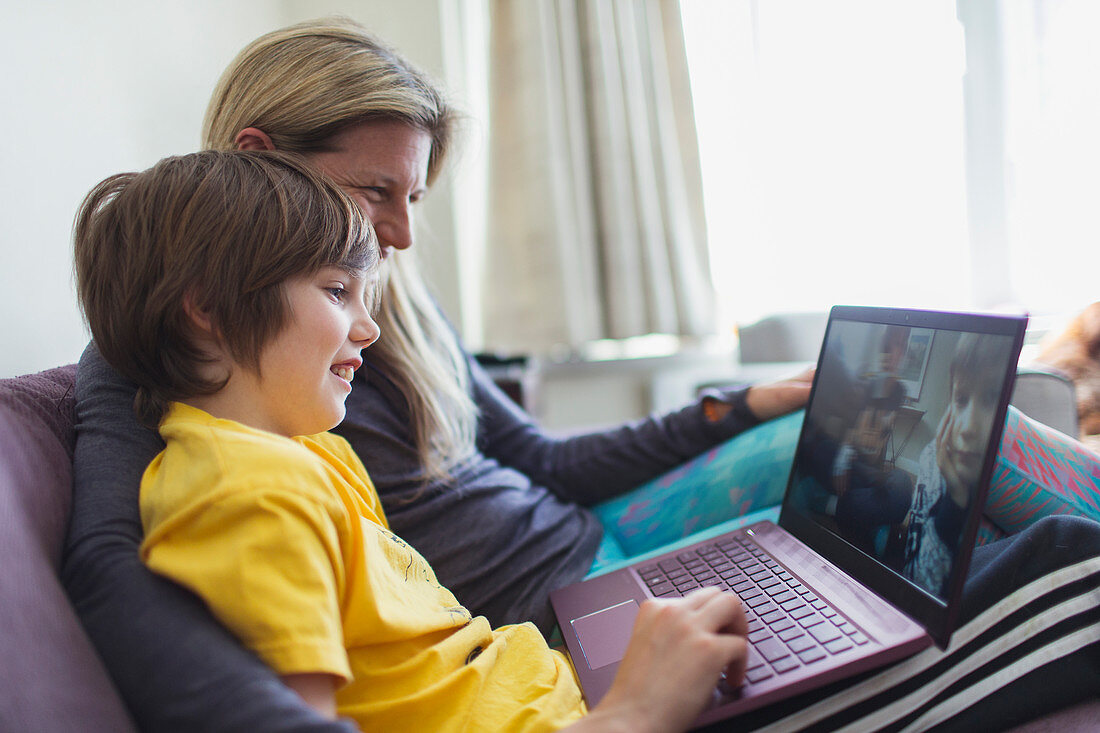 Mother and son using laptop on sofa