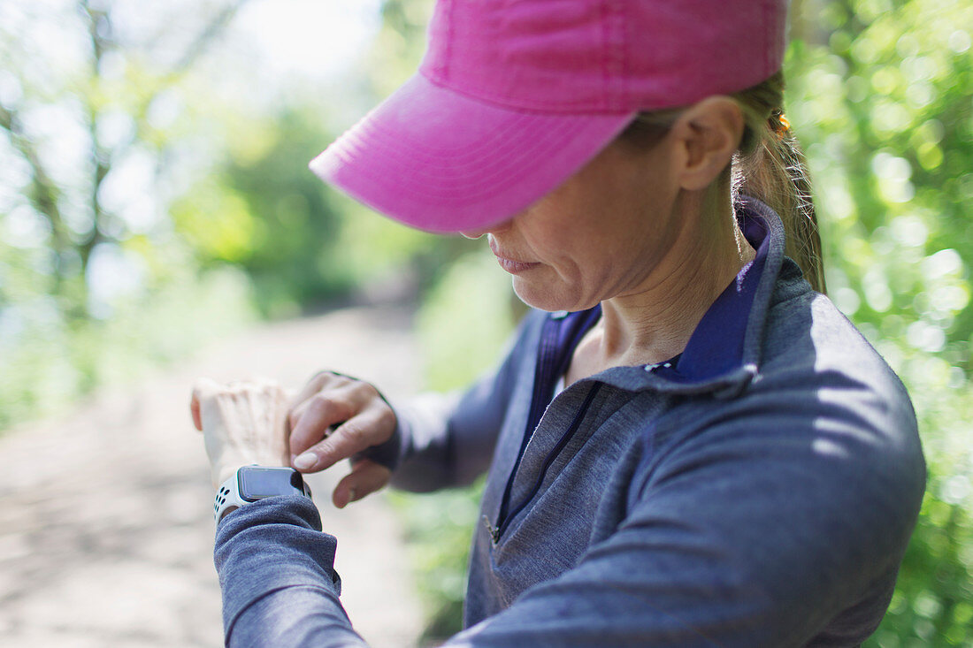 Female jogger with smart watch on hiking trail