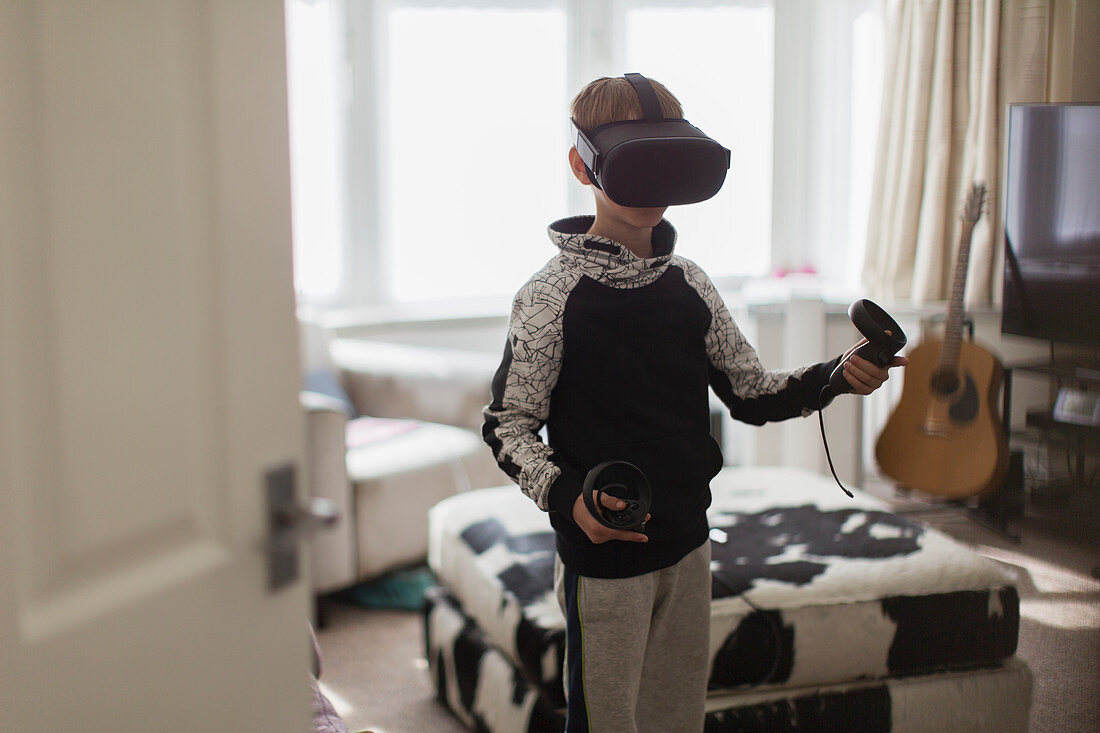 Boy playing video game with VRS goggles in living room
