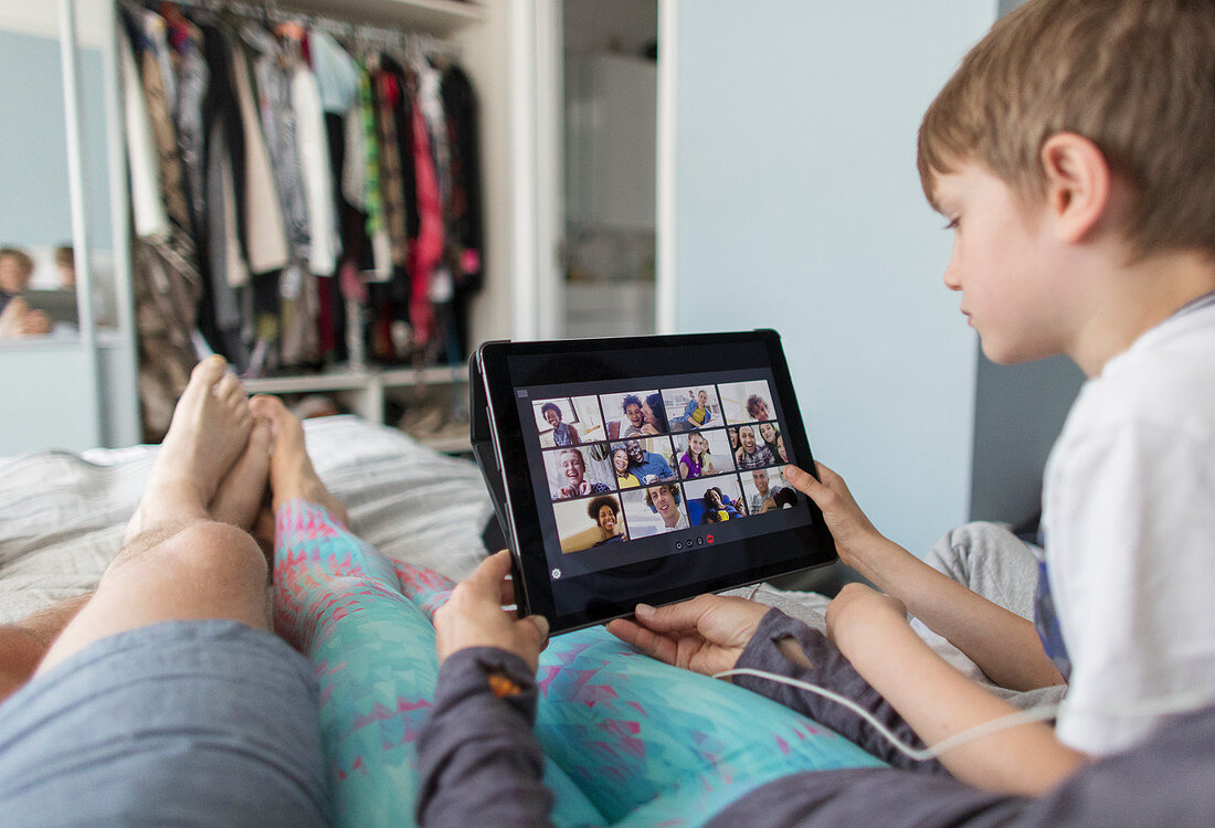 POV family with tablet video chatting with friends on bed