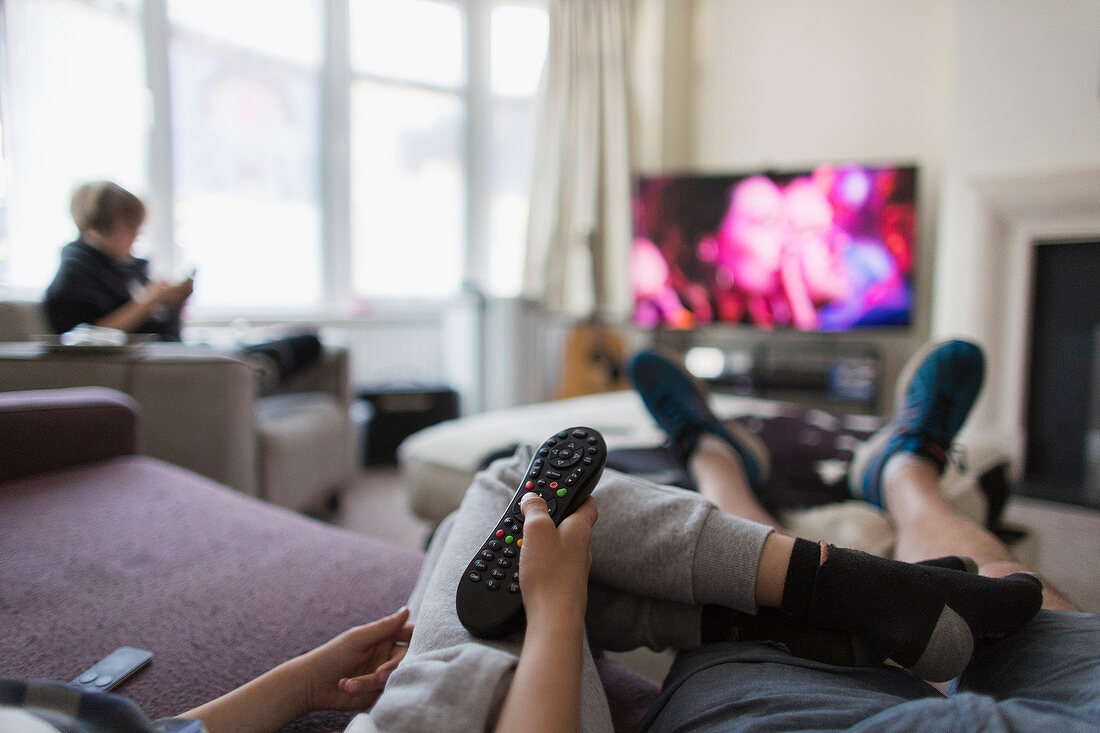 POV family with remote control watching TV in living room