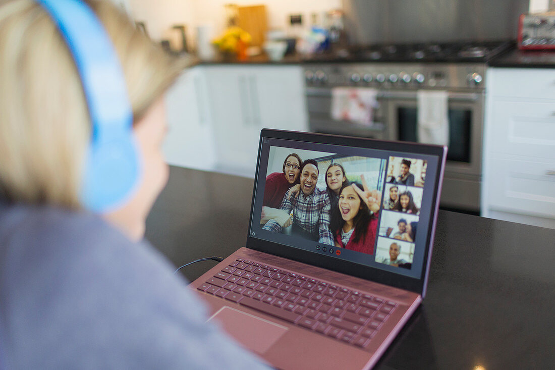 Woman with laptop video chatting with friends in kitchen