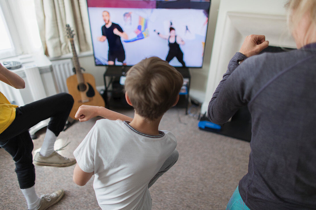 Mother and sons exercising online at TV in living room