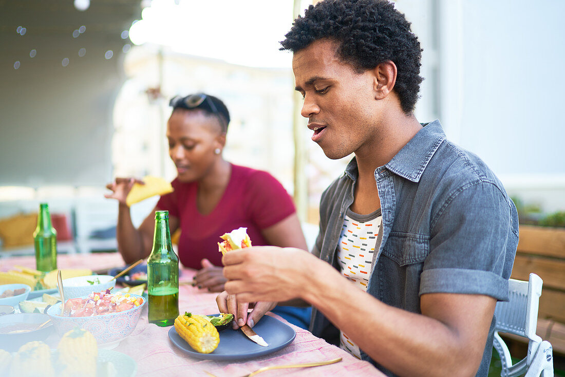 Young man eating taco lunch at patio table