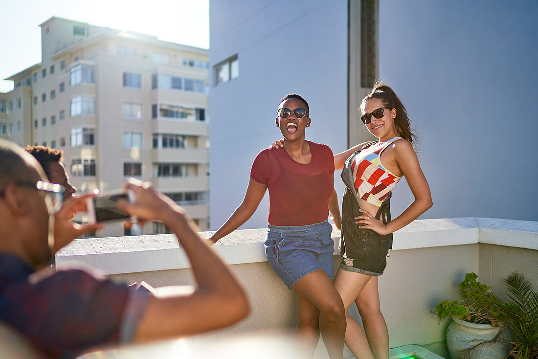 Happy young women friends posing for photo on sunny balcony