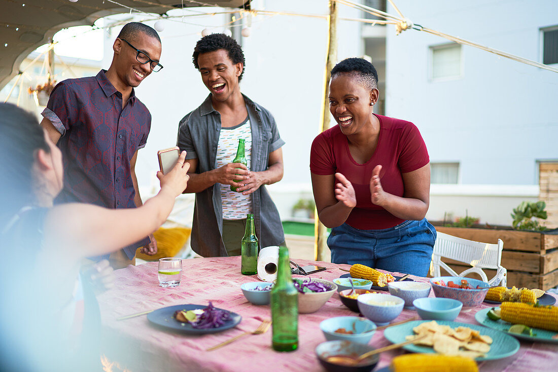 Happy young friends eating lunch at patio table