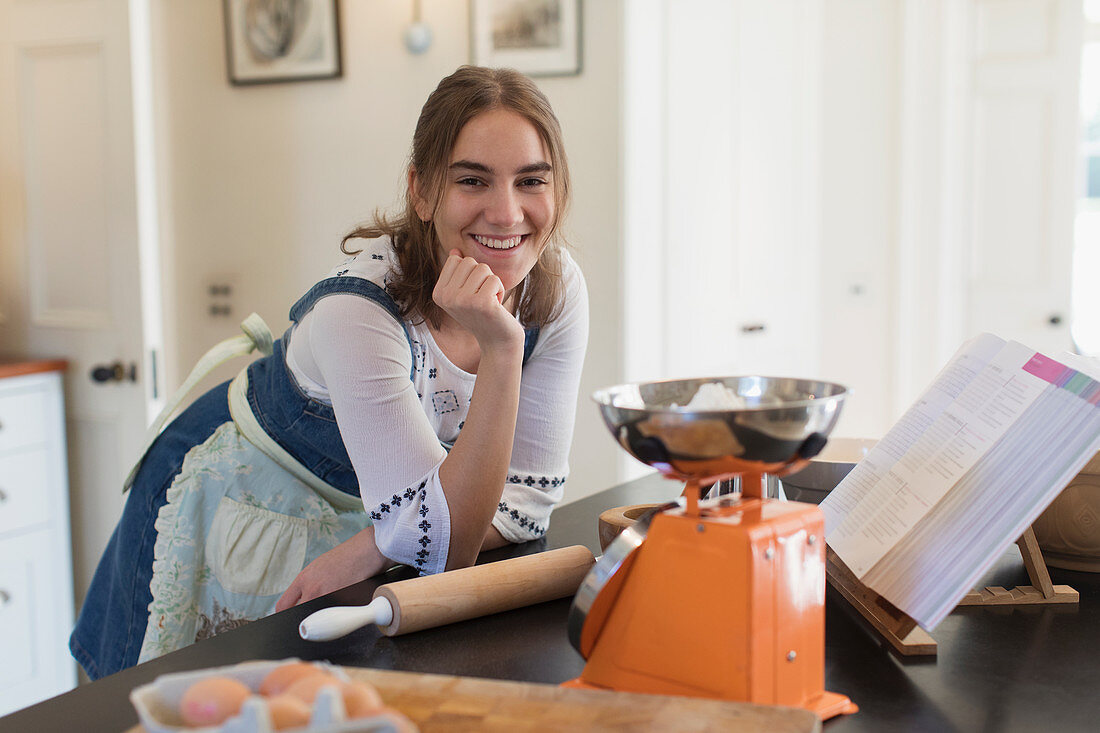 Portrait happy teenage girl baking in kitchen