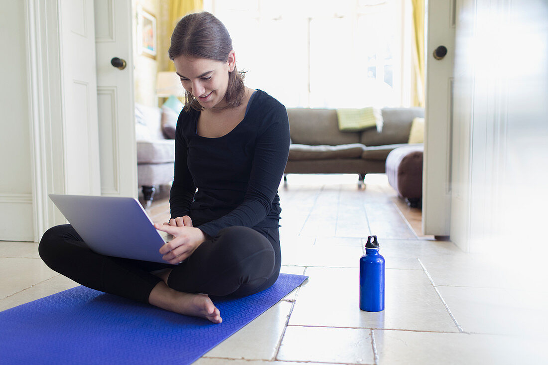 Teenage girl taking online yoga class with laptop