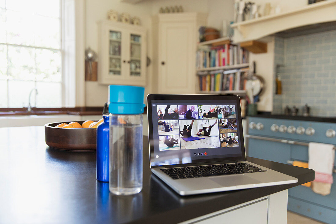 Exercise class streaming on laptop screen on kitchen counter