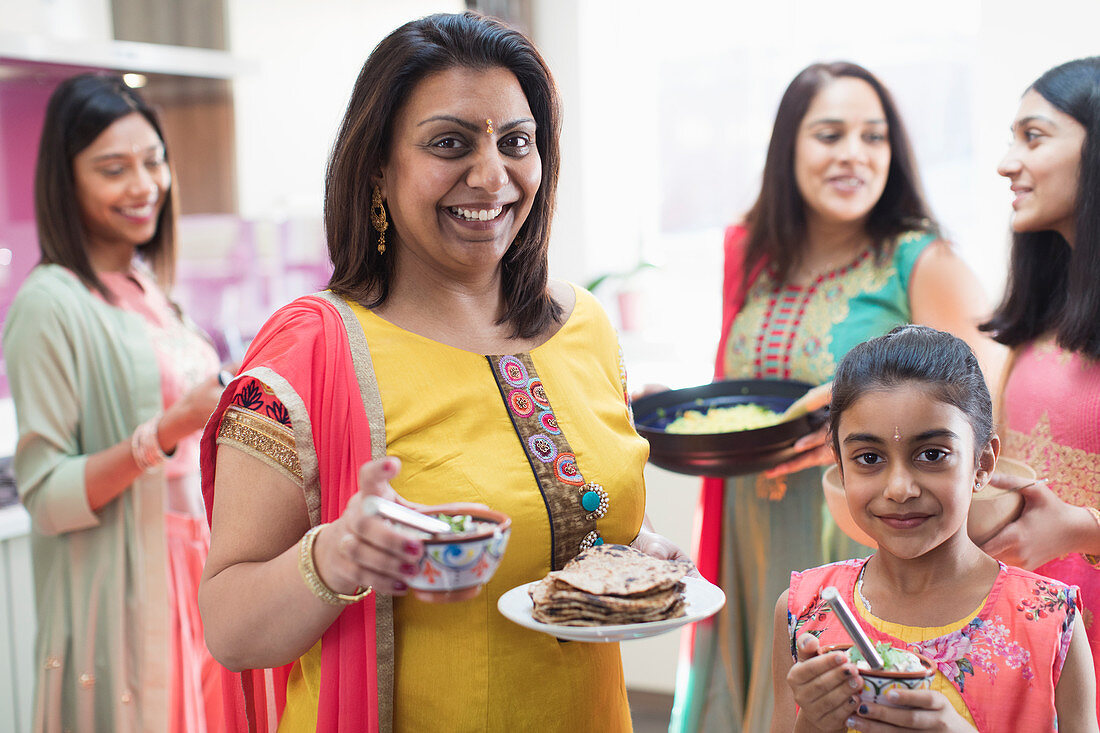 Portrait happy mother and daughter in Indian saris with food