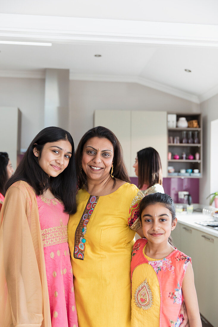 Happy Indian mother and daughters in saris in kitchen