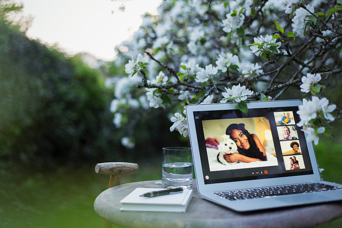 Friends video chatting on laptop screen in tranquil garden