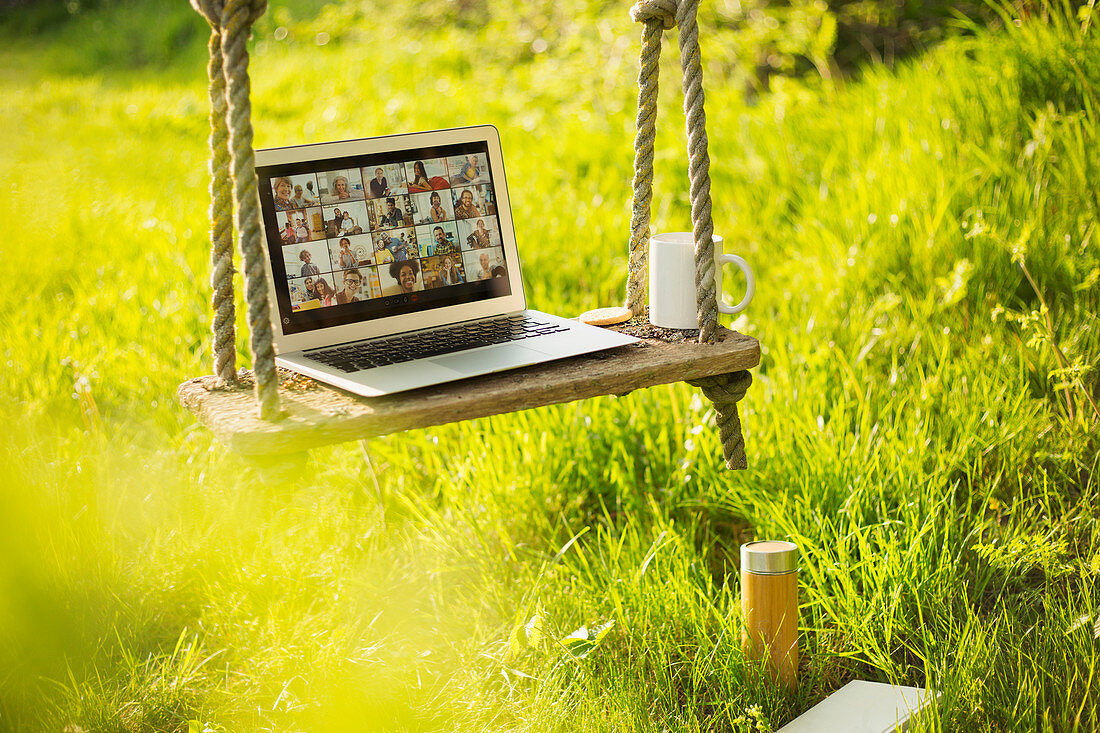 Friends video chatting on rustic bench in sunny garden