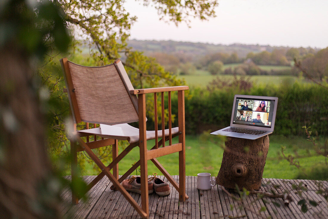 Colleagues video chatting on laptop screen on rural balcony