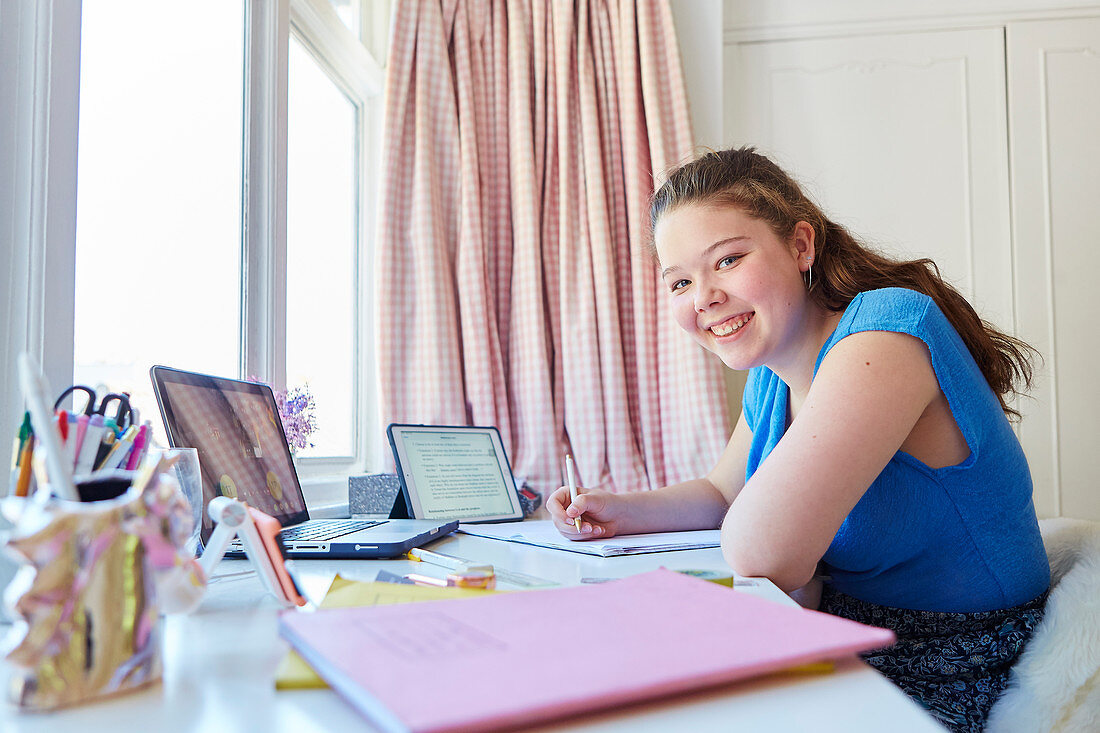 Portrait confident girl homeschooling at desk in bedroom