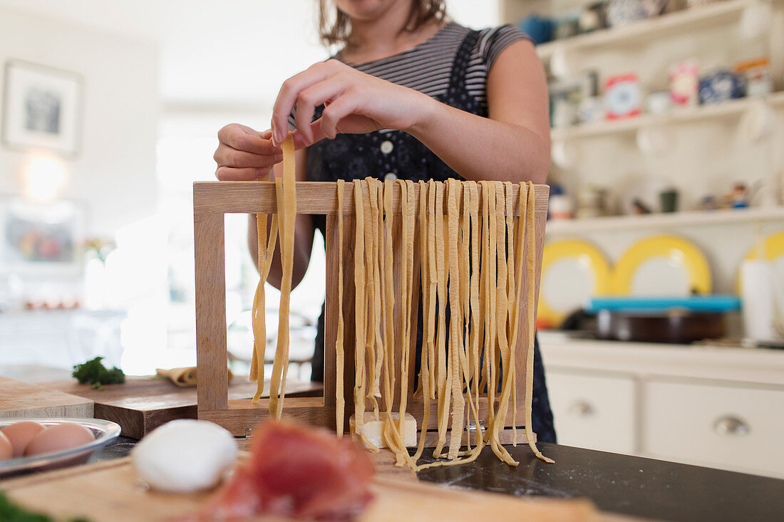 Teenage girl making fresh homemade pasta in kitchen