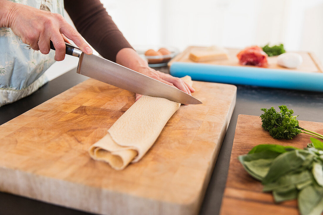Woman cutting fresh homemade pasta on cutting board
