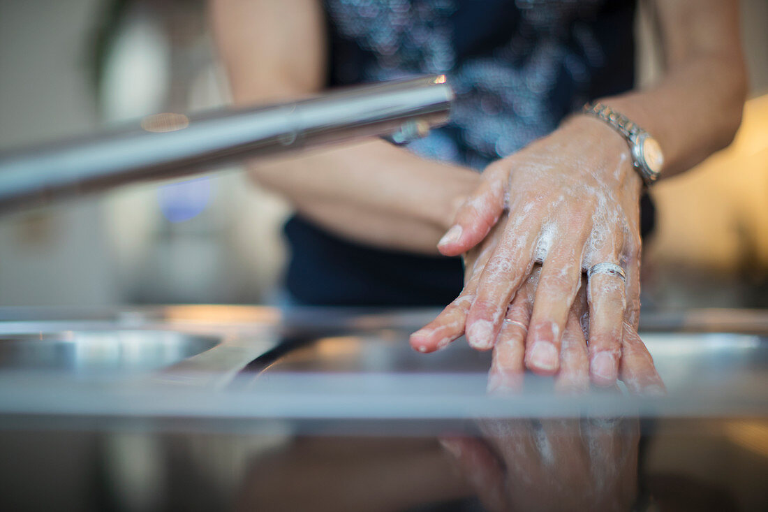 Close up woman washing hands with soap at kitchen sink