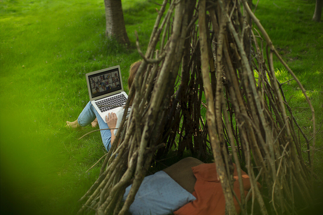 Woman video conferencing with friends on laptop at teepee