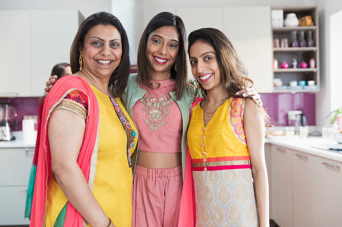 Portrait happy Indian sisters in saris in kitchen