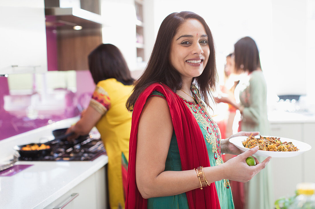 Portrait happy Indian woman in sari cooking food in kitchen