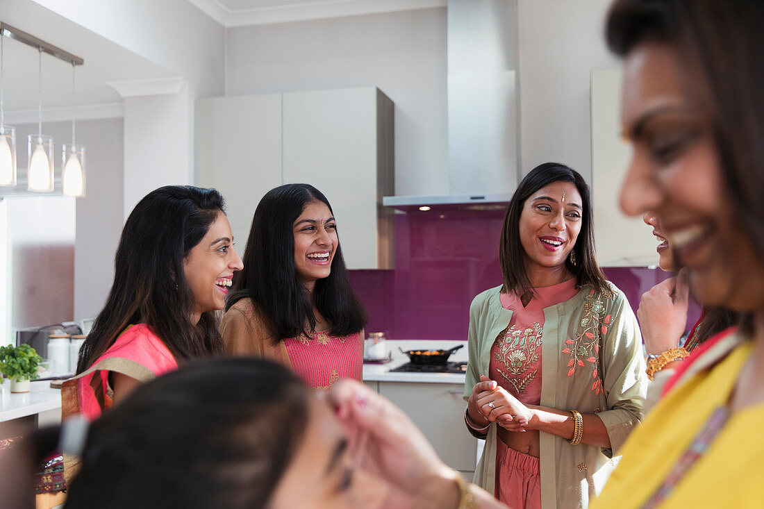Happy Indian women in saris talking in kitchen