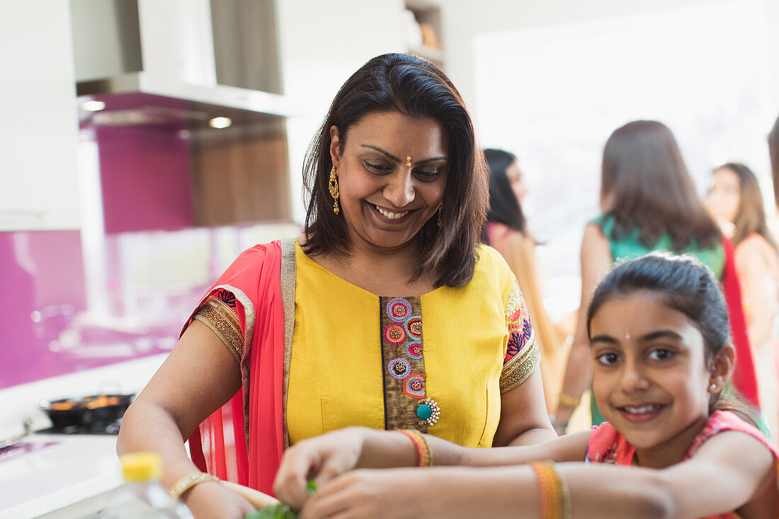 Indian mother and daughter in saris cooking food in kitchen