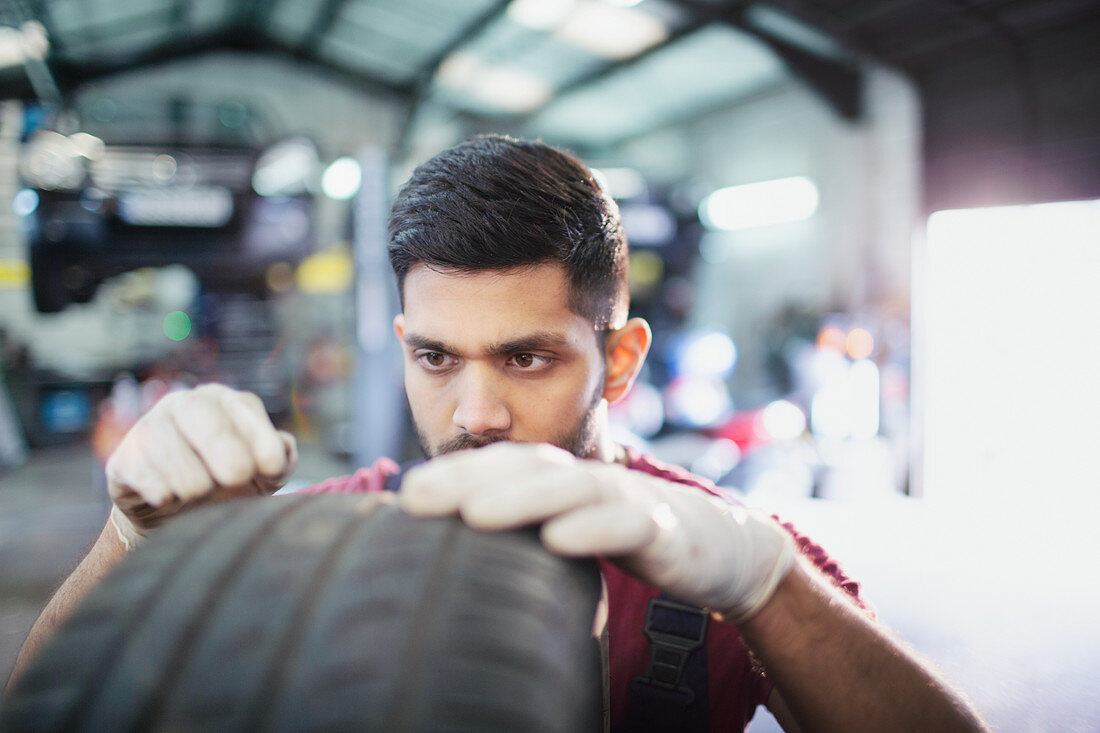 Focused male mechanic examining tire