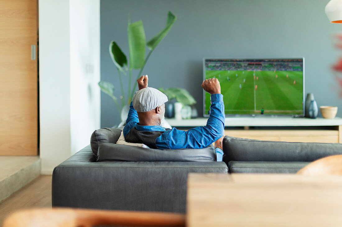 Excited man cheering, watching soccer match on TV
