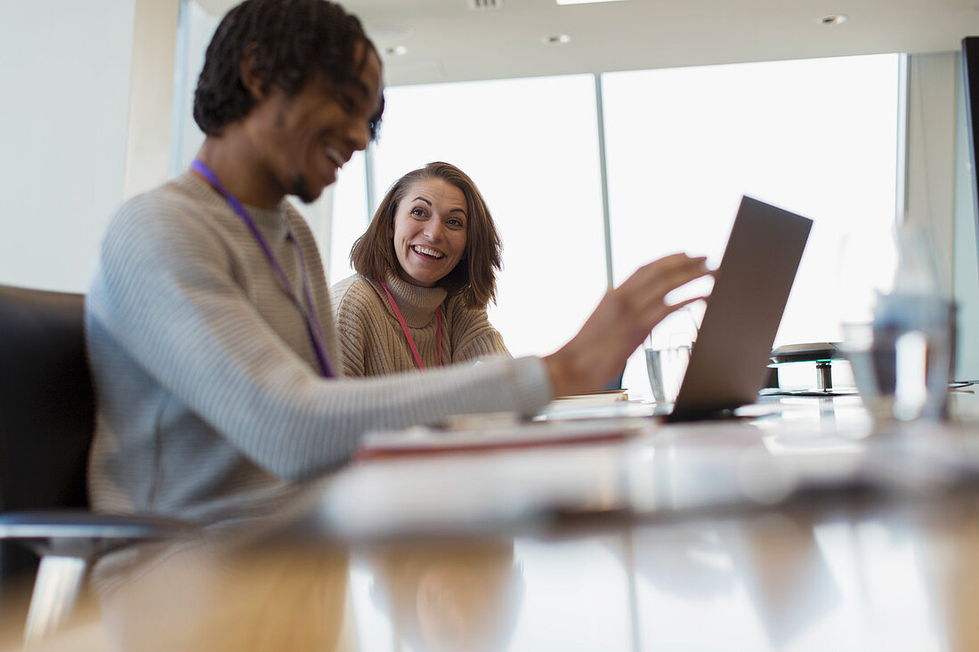 Smiling business people using laptop