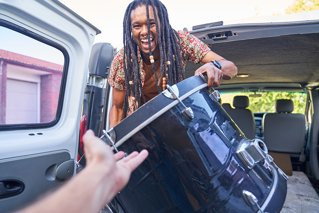 Happy male musician loading drum into van