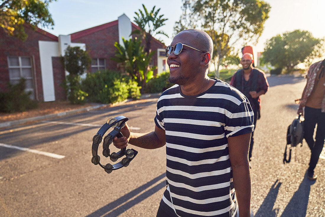 Happy male musician with tambourine on street
