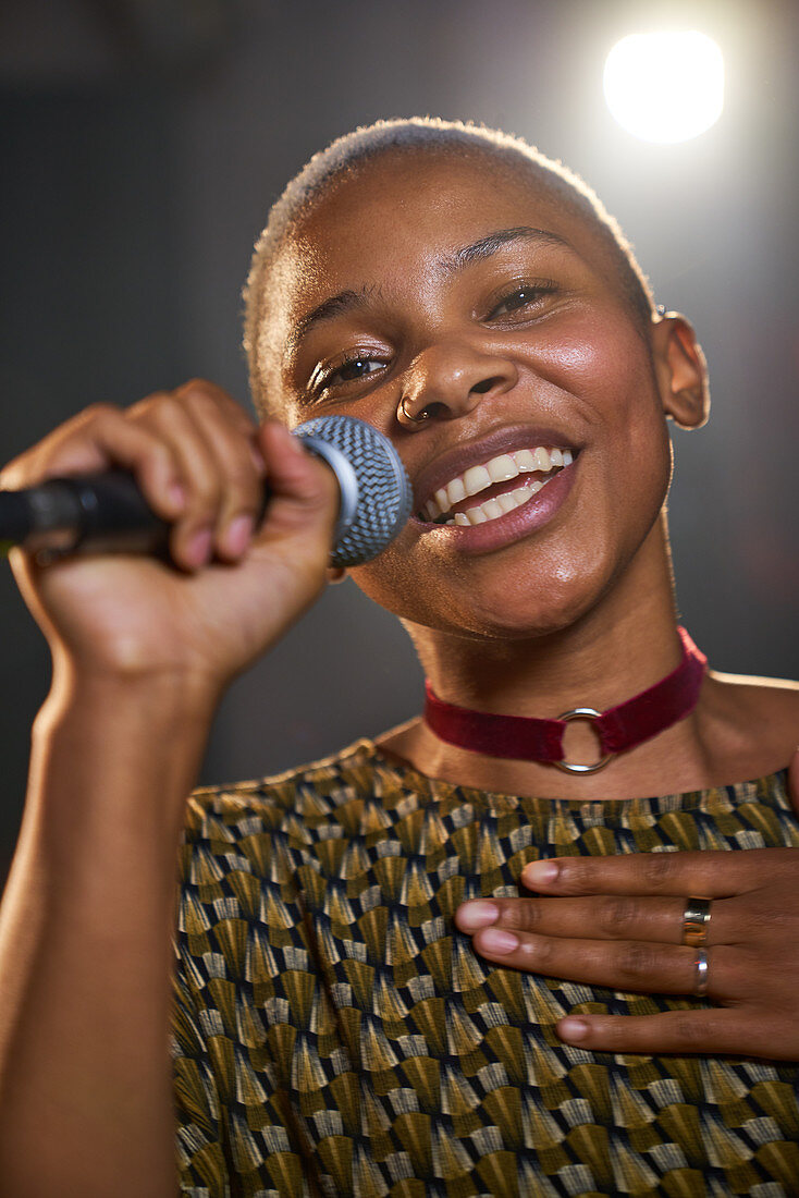 Portrait female musician singing into microphone