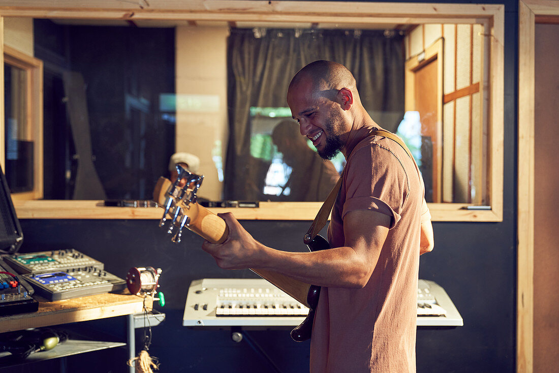 Male musician playing guitar in recording studio