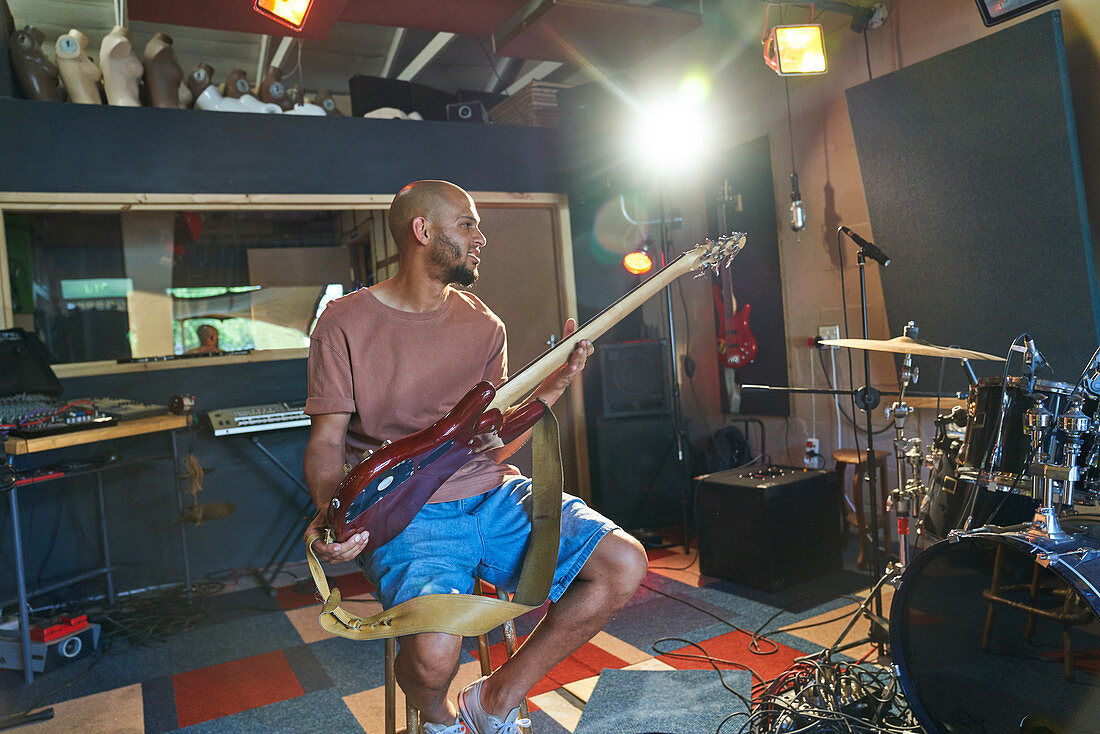 Male musician playing guitar in recording studio