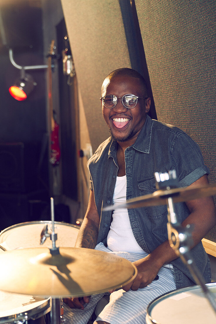 Portrait happy male drummer practicing at drums
