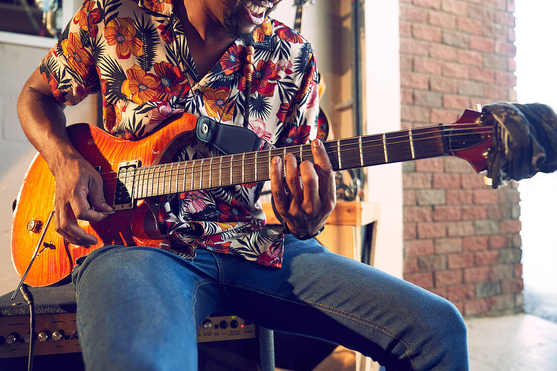 Male musician playing electric guitar in garage