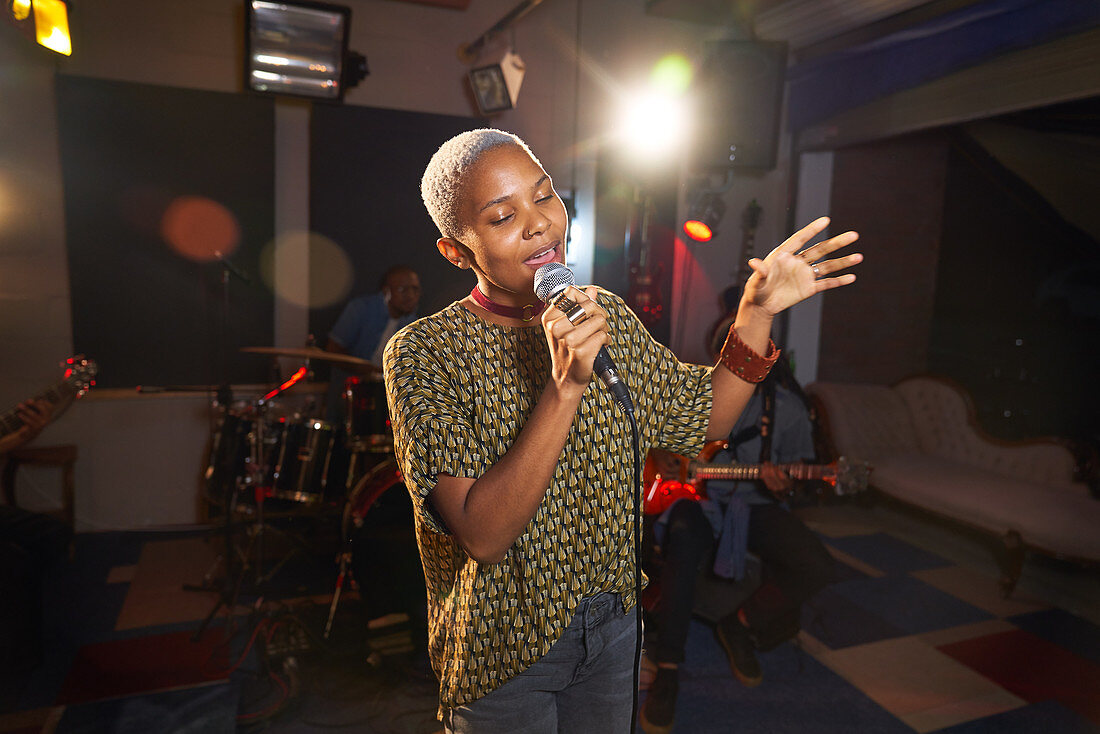 Young female musician singing into microphone