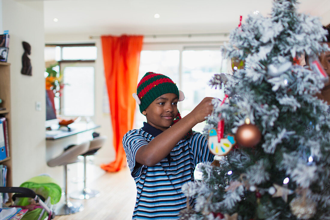Boy decorating Christmas tree in living room