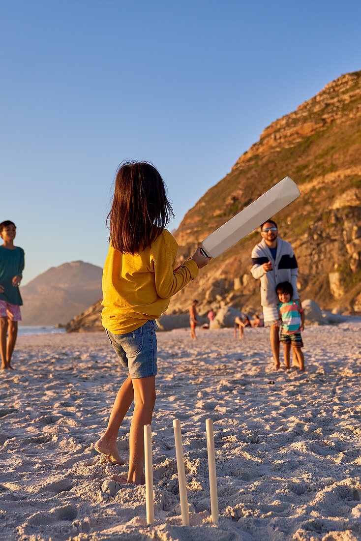 Family playing cricket on summer beach
