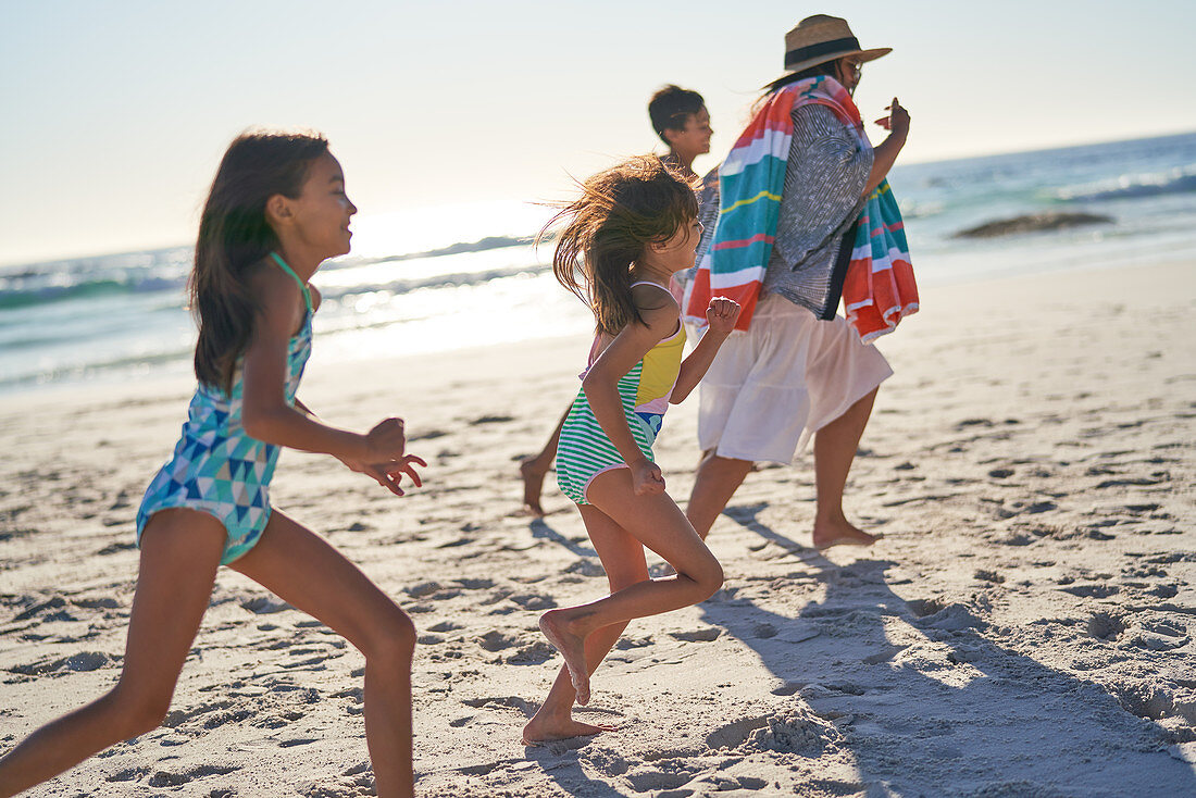 Playful family running on sunny ocean beach