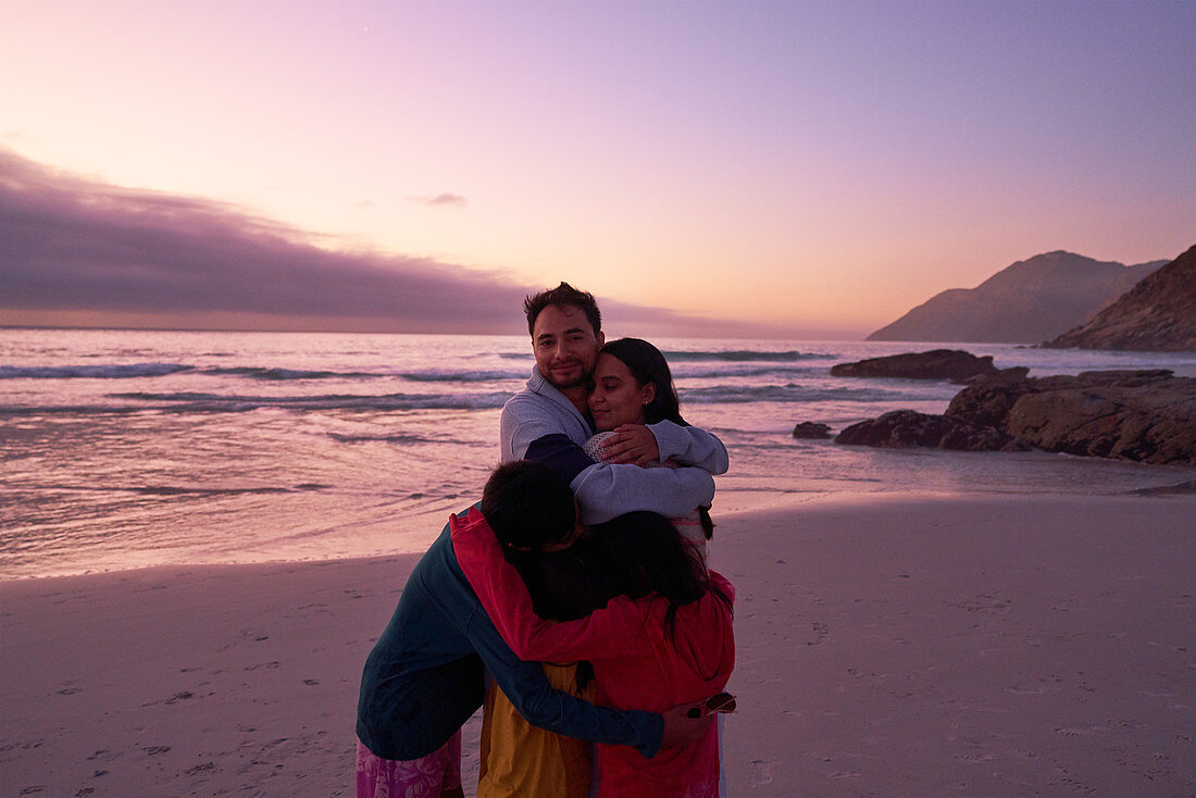 Family hugging on sunset ocean beach, Cape Town