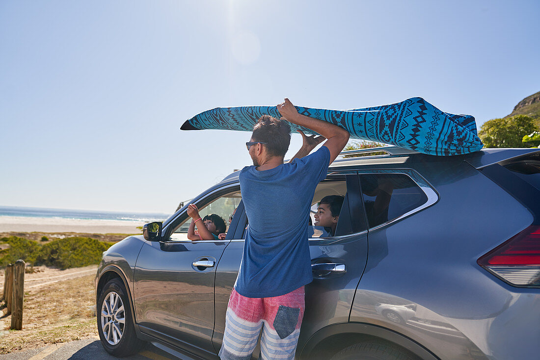 Man removing surfboard from top of car