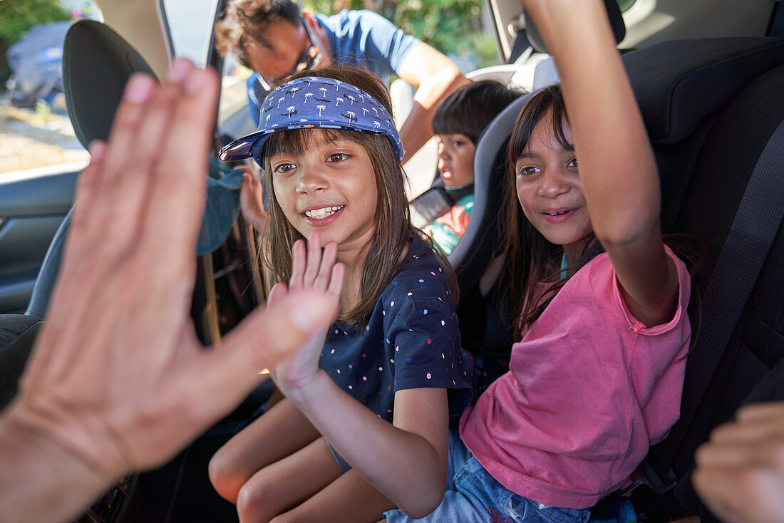 Happy kids high-fiving in back seat of car