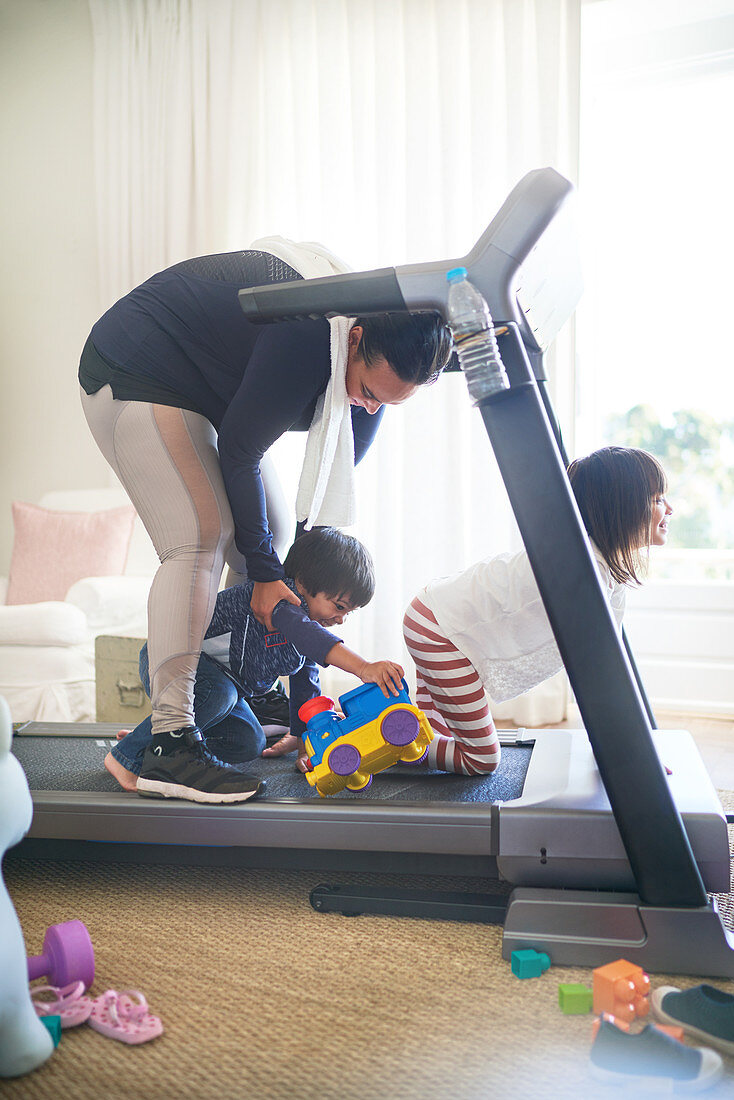 Kids with toys distracting mother on treadmill