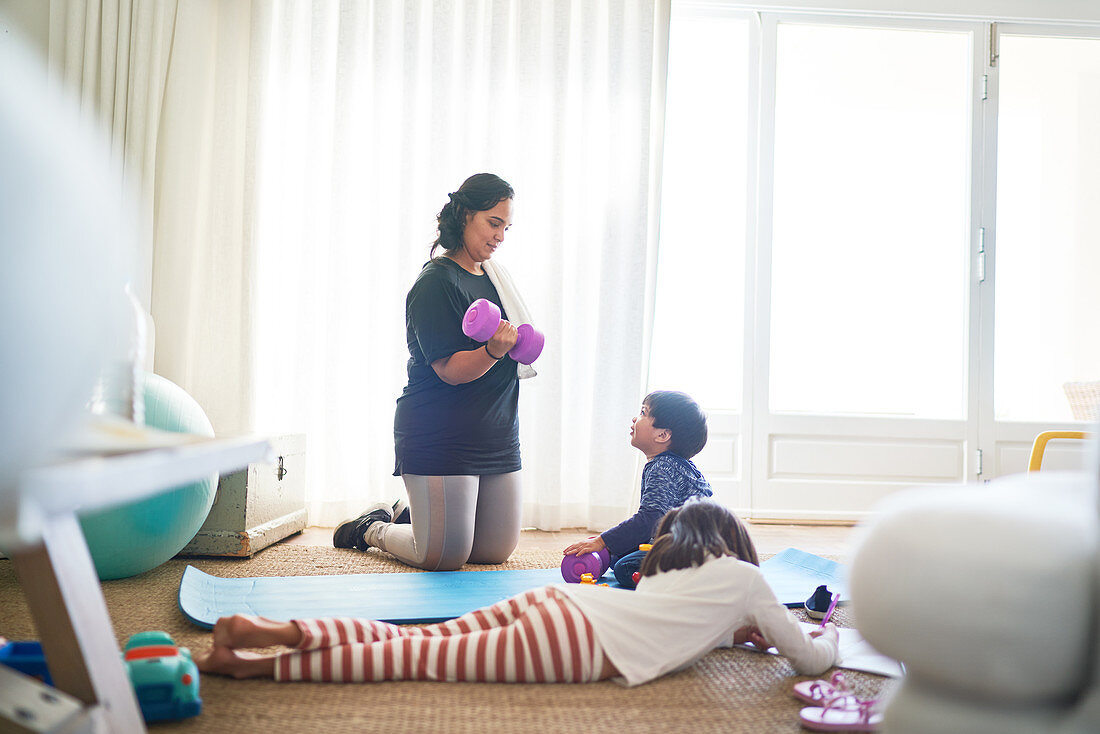 Boy watching mother exercise with dumbbells
