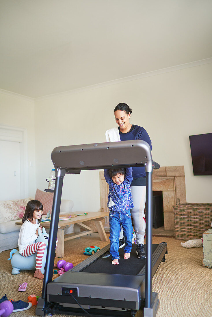 Mother and son walking on treadmill in living room