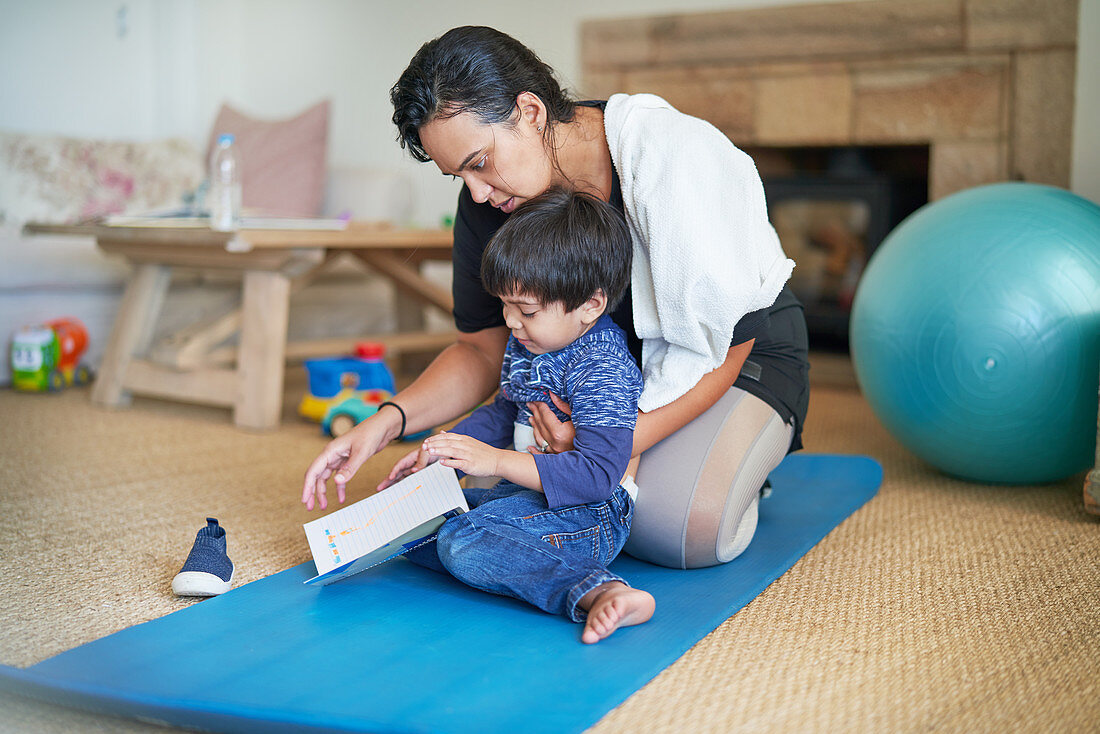 Mother and son on yoga mat in living room