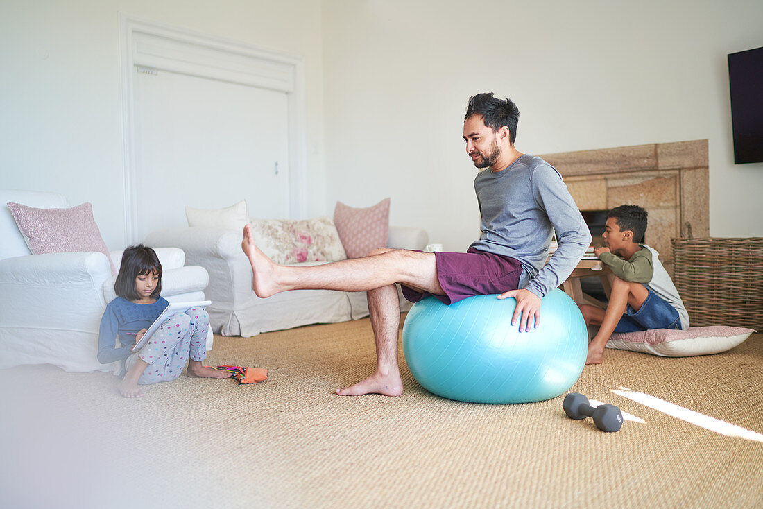 Father exercising in living room with kids