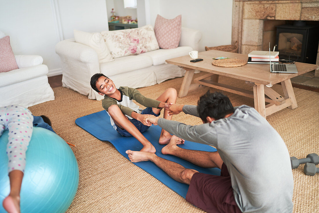 Playful father and son exercising on yoga mat